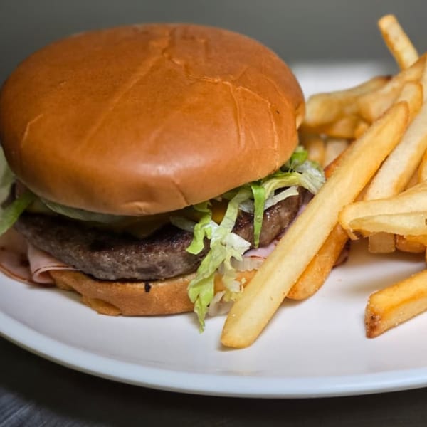 A hamburger with lettuce, onions, and cheese, served with a side of golden french fries.