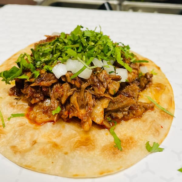 A close-up of a Los 3 Regios Mexican Restaurant taco with shredded meat, cilantro, and diced onions.