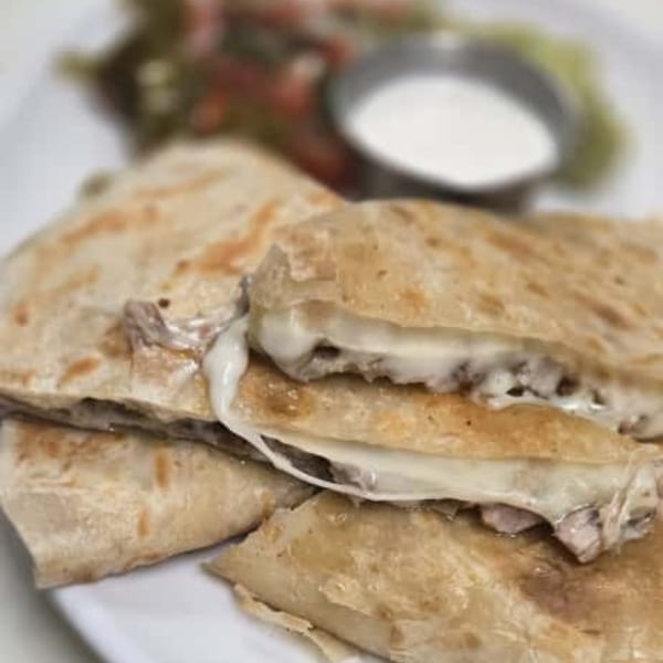 Cheesy quesadillas with meat filling, served with a side of sour cream and salad.
